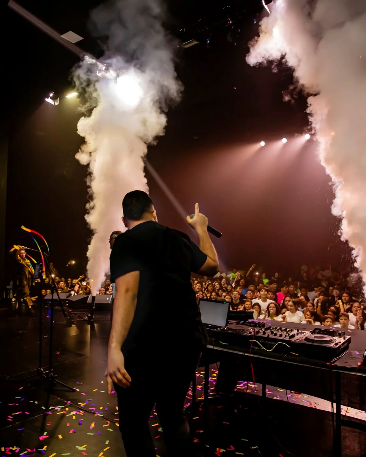DJ Vitor Capoia no palco com efeitos de CO2 e público
